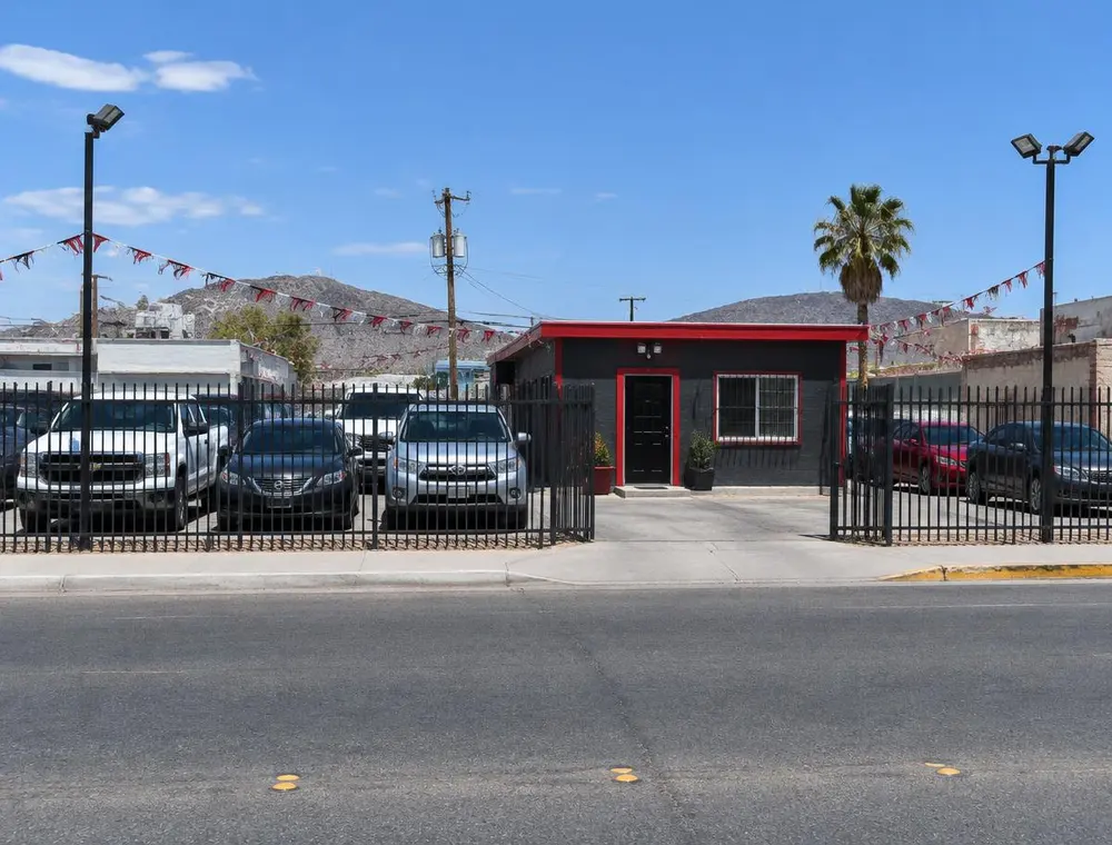 Fachada de un lote de autos con reja y oficina gris con rojo (foto ilustrativa)